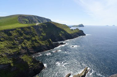 Ireland 'ın büyüleyici güzelliğini yakalayın. Yumuşak güneş ışığı tarafından öpülen yeşil kayalıklar. Huzurlu mavi bir denizin ve sonsuz bir gökyüzünün arka planına karşı..