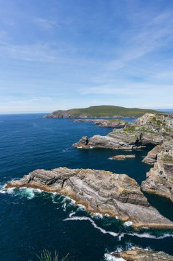 Ireland 'ın dikey uçurumlarının nefes kesici güzelliğini yakalayın, çarpıcı bir ışıkla yıkanmış, canlı bir mavi gökyüzü ve ışıl ışıl deniz manzarasına karşı..