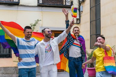Neşeli ve neşeli iki eşcinsel çift, geçit töreni için LGBTQ sembolleriyle süslenmiş bir şekilde kapılarından çıkarken gururla kucaklaşıyor..