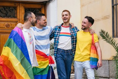 LGBTQ sembolleriyle süslenmiş dört neşeli eşcinsel arkadaş, mutlulukla evlerinden çıkarken bağlarının tadını çıkarıyorlar..