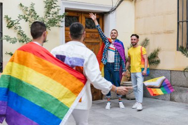 Sevinçten deliye dönmüş iki eşcinsel çift, LGBTQ 'nun gururlu eşyalarından oluşan bir koleksiyonla birbirlerini evlerinin girişinde selamlıyorlar..