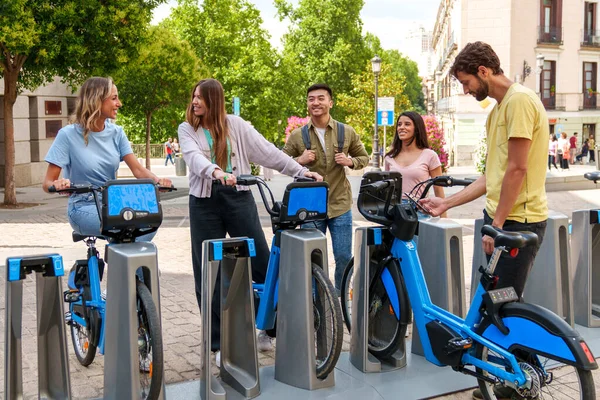 Beş neşeli, çeşitli genç, güneşli bir günde şehirdeki bir bisiklet kiralama şirketinden elektrikli bisiklet kiralıyorlar.
