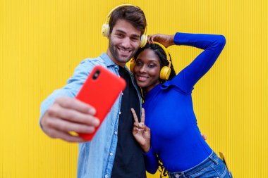 İki arkadaş, bir Kafkasyalı ve bir Afrikalı, birlikte canlı müziğin keyfini çıkarıyorlar, sarı arka planda renkli bir selfie çekiyorlar..