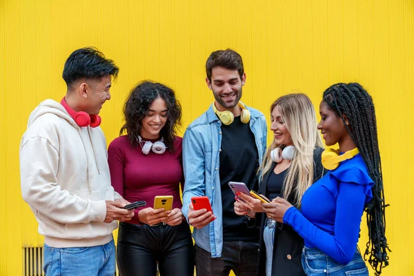 A colorful photograph capturing five ethnically diverse friends happily chatting on their phones, exuding pure joy against a vibrant yellow background.