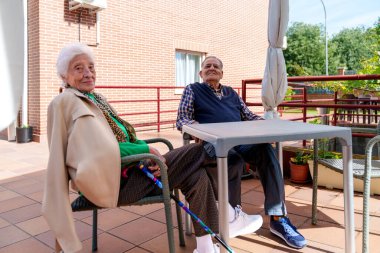 Huzurevinin güneşli bahçesinde, yaşlı bir erkek ve kadın güneşli bir günde neşe ve neşe bulurlar..