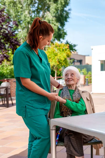 一位老妇人牵着她的手 在一家疗养院的院子里 一个阳光明媚 花园繁茂的养老院里找到了快乐 — 图库照片
