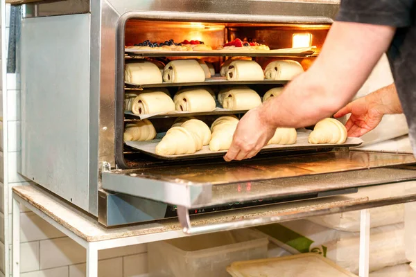 Zdjęciu Bliska Anonimowy Piekarz Umiejętnie Umieszcza Tacki Rogalikami Ciastkami Czekoladowymi — Zdjęcie stockowe