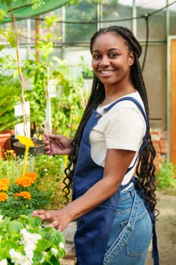 Canlı çiçeklerle dolu verimli bir bahçeye dalmış parlak Afrikalı kadın, doğanın kaleydoskopunun özünü canlı bir portrede yakalıyor..