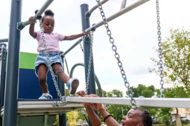 Korkusuz ama cesur, 5 yaşındaki Afrikalı bir kız titrek bir parktaki köprüde ihtiyatlı adımlarla yürüyor..