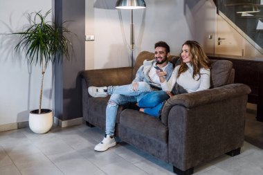 Modern ev televizyonlarında online dizi izleyen beyaz bir çift. Romantik bir akşamda bir çiftin yaşam tarzı. Yurt içi yaşam tarzı.