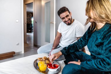 Pijamalı genç bir çiftin kocası onu yatakta bekleyen karısı için hazırladığı kahvaltıyı getiriyor. Koca, karısına sürpriz olsun diye kahvaltıyı yatakta bırakır. Romantik kahvaltı. Tepside kahvaltı..