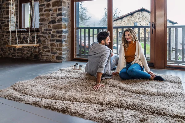 A caucasian couple relaxing in the attic of their home with a beautiful window and natural light, lifestyle on a romantic evening. Young tourist couple enjoying a rural vacation house.