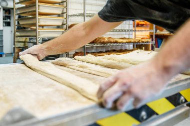 Fırıncının elleri çelik bir masanın üzerinde ekmek hamuru hazırlıyor..