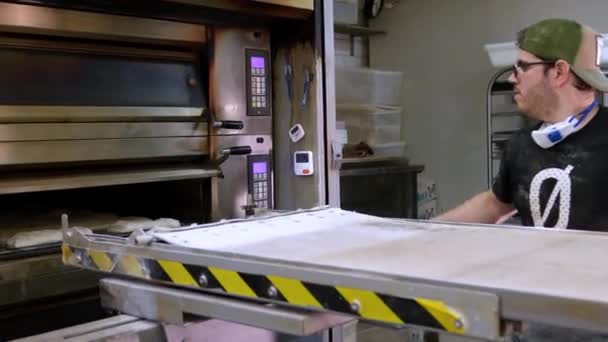 Młody Piekarz Sprawdza Bochenki Piekarniku Przemysłowym Zapewniając Doskonałą Jakość Wypieku — Wideo stockowe