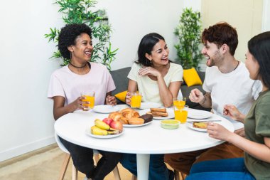 Neşeli çeşitli gruplar, meyveli ve pastalı sağlıklı bir kahvaltıdan zevk alıyor, kahkahaları paylaşıyorlar..