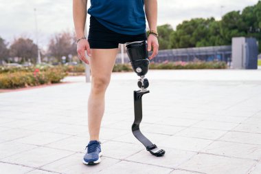 Koşu bıçağı protezli tanınmayan erkek sporcu şehir parkında eğitime hazır, uyumlu sporları somutlaştırıyor..