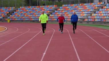 Mavi spor giyim giymiş, sağlık ve dayanıklılık sergileyen üç yaşlı beyaz adam.