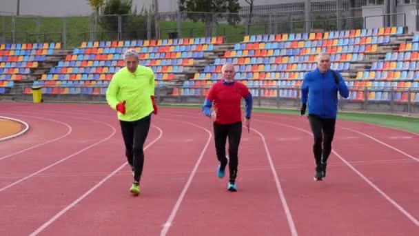 三名身穿蓝色运动服的白人老年男子在跑道上跑步 表现出健康和耐力 — 图库视频影像