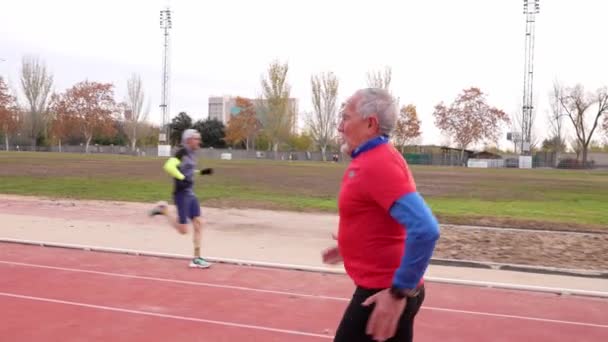 Starszy Biały Mężczyzna Czerwonej Odzieży Sportowej Biegnie Torze Pokazując Zdrowie — Wideo stockowe