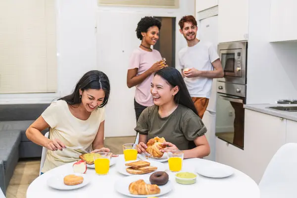 Group of diverse friends enjoying a hearty breakfast together, engaging in lively conversation in a bright, modern kitchen.