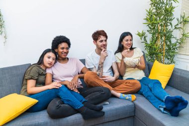 Gülen arkadaşlar bir kanepede toplandılar, bir evde komedi filmi izlerken komik bir sahnenin tadını çıkardılar..