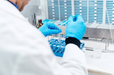 Test tüplerinde numuneler üzerinde uzmanlaşan, bir hastanenin klinik laboratuvar ortamında özenle çalışan tanınamayan bir sağlık görevlisi..