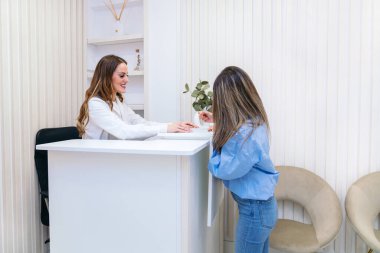 Bir müşteri, estetisyen, cilt bakımı konusunda uzman tavsiyesi verirken, kişiselleştirilmiş bir yaklaşımın altını çizerek dikkatle dinler..