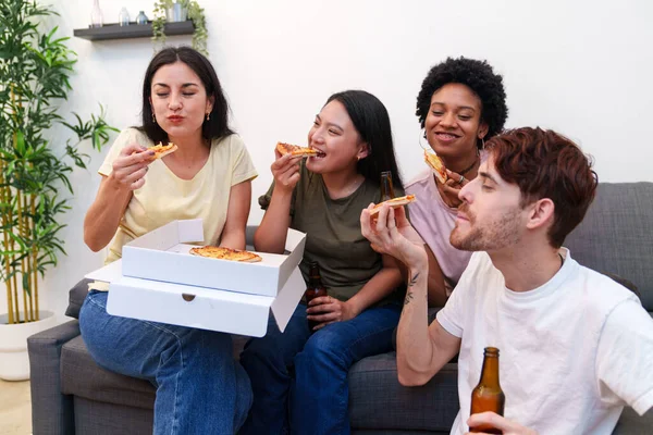 A group of friends cheerfully eat pizza and share beers while celebrating a birthday, creating memories in their comfortable living room.