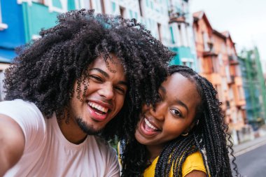 Coşkulu Latin arkadaşlar canlı bir caddede neşe dolu bir selfie çekiyorlar..