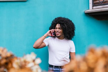 Turkuaz duvardan konuşan afro saçlı bir adam..