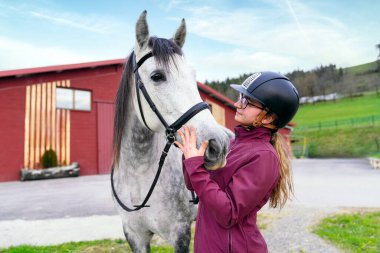 Genç binici kadın atını seviyor, açık havanın tadını çıkarıyor..