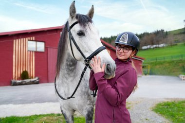 Beyaz bir atla hassas bir anı paylaşan genç bir binicinin yakın çekimi..