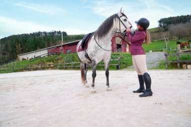Sürücü kumlu arenada atının dizginlerini ayarlıyor..