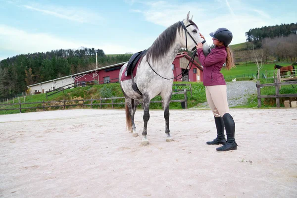 Sürücü kumlu arenada atının dizginlerini ayarlıyor..