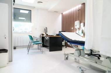 Muayene için muayene yatağı ve masası olan temiz bir klinik odası..