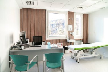 Ahşap aksanlı ve tıbbi teçhizatlı parlak klinik odası.