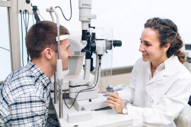 Göz uzmanı hastanın muayenesi için kesik lamba kullanıyor.