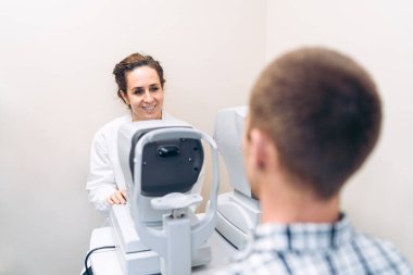 Hasta göz muayenesine girerken kadın optometrist gülümsüyor.