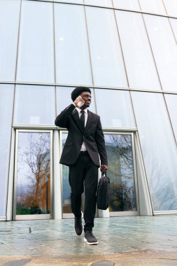 Odaklanmış, genç bir Afrikalı adam hareket halindeyken iş yapıyor..