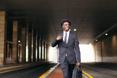 Takım elbiseli Afrikalı bir işadamı şehirde güven içinde yürüyor..