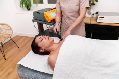 Özenli terapist tarafından boyun elektroterapisi gören sakin bir hasta..