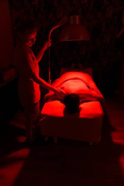 Bir hasta terapistin bakımı altında rahatlatıcı bir kızılötesi terapi geçirir..
