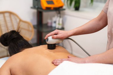 Fizyoterapist, hastanın omuriliğinde şok terapi cihazı kullanıyor..