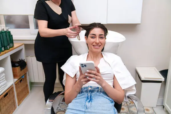 Eine Kundin Interagiert Während Der Haarpflege Mit Ihrem Telefon — Stockfoto