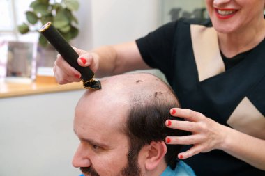 Expert cuts remaining hair before hairpiece fitting. clipart