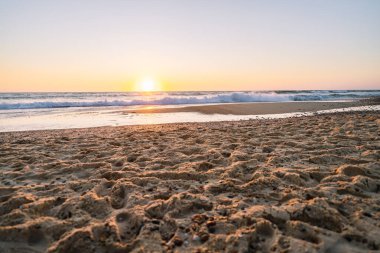 Altın güneş batıyor, okyanus dalgaları üzerinde parıldıyor.
