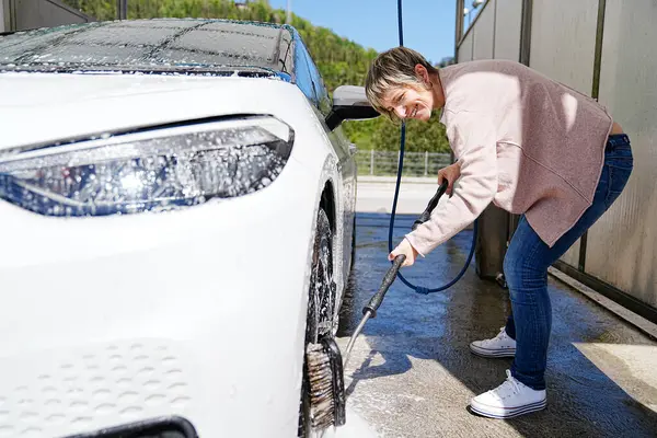 一个精力充沛的女人在洗澡间用电力洗车 免版税图库图片