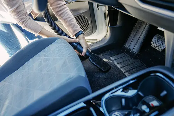 一个女人把注意力集中在清洁上 用吸尘器把她的车的地板吸空 图库图片