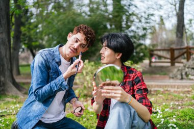 LGBT 'li Çinli bir adam parkta makyaj yaparken gülüyor..