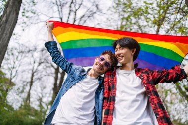 Çinli eşcinsel çift açık havada canlı bir LGBT bayrağı tutuyor, sevgi ve gurur gösteriyorlar..